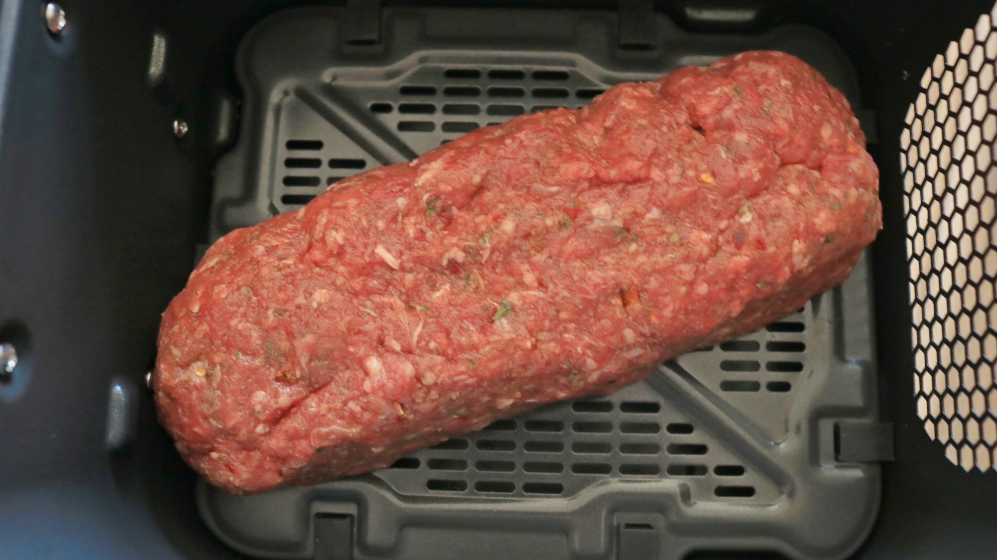 Raw meatloaf in an air fryer basket.