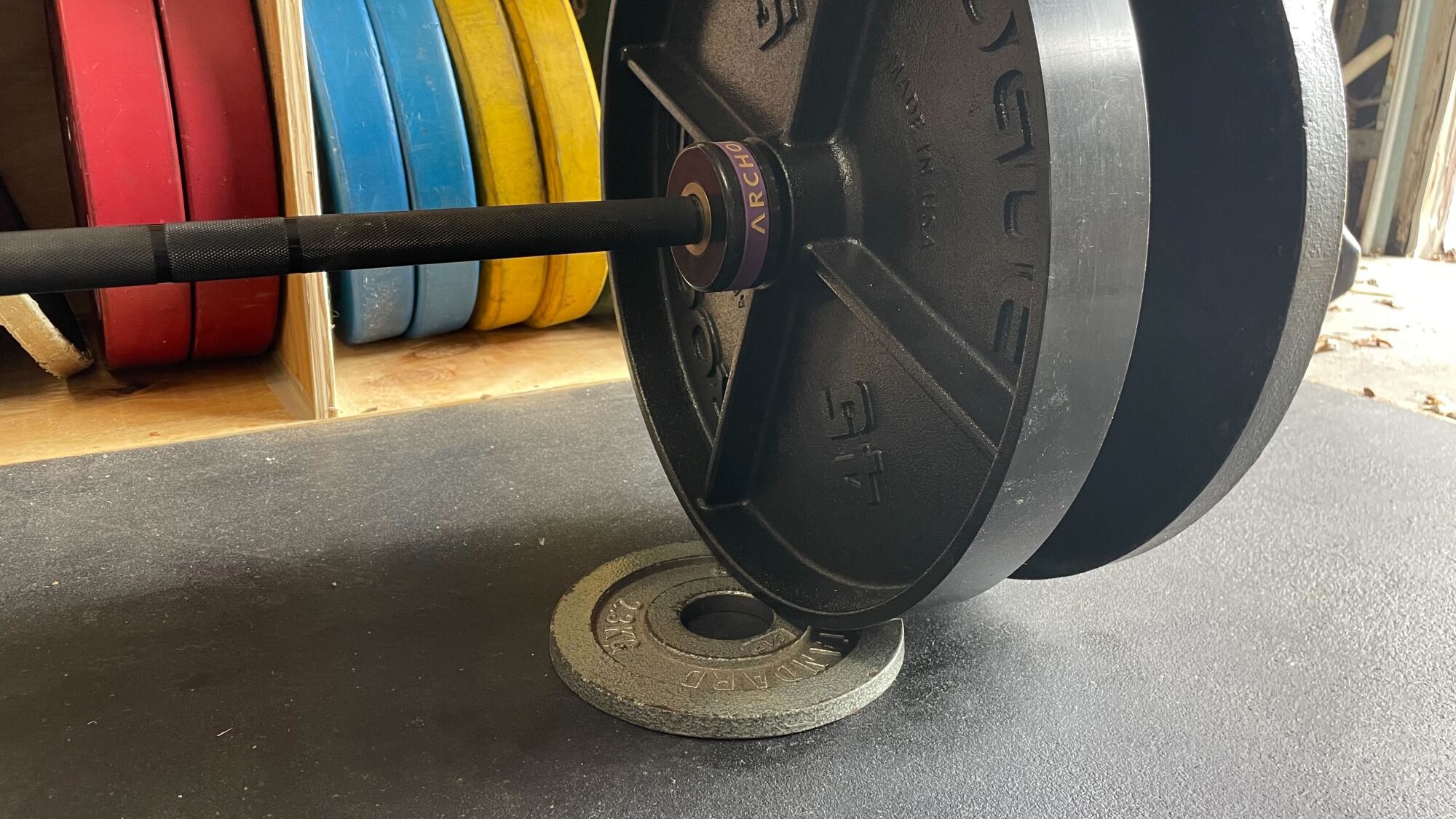 a tiny weight lying on the ground, slightly propping up one end of a barbell with plates