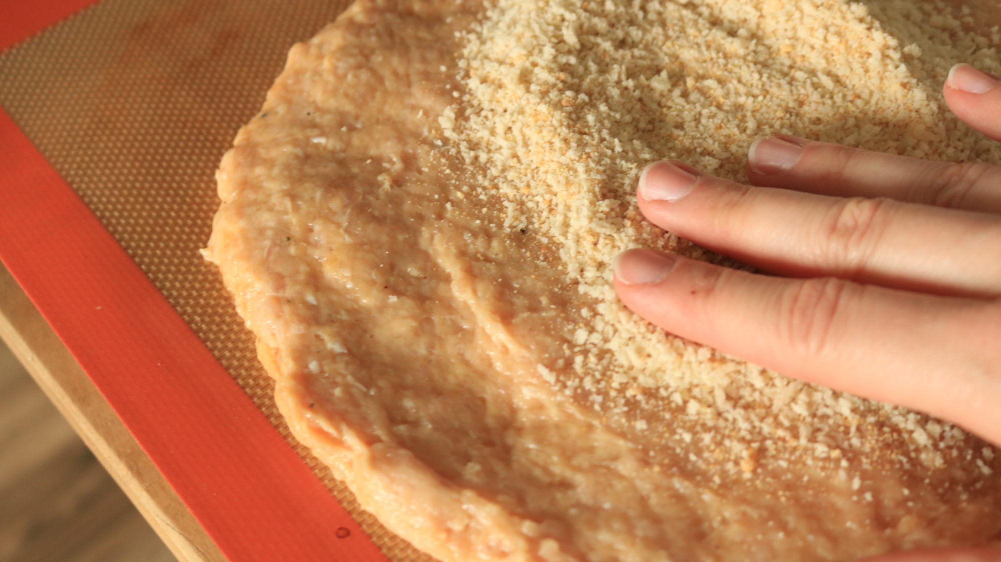 Fingers patting breading onto crust