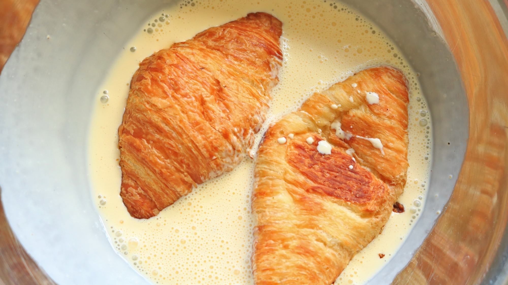 Croissant halves soaking in custard.